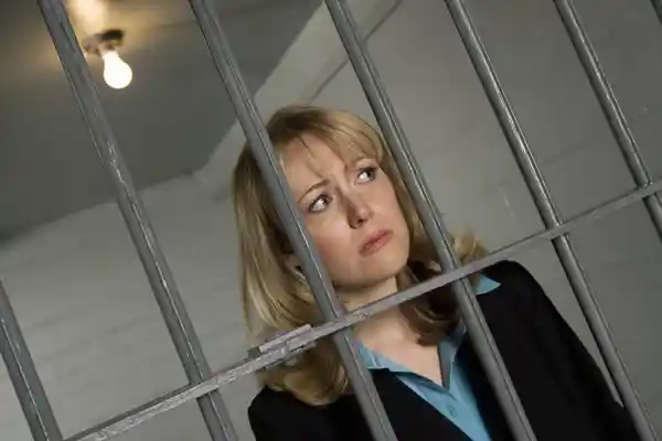 A woman in business attire behind bars
