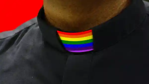 A photo of a priest with a clerical collar in the pride rainbow colors